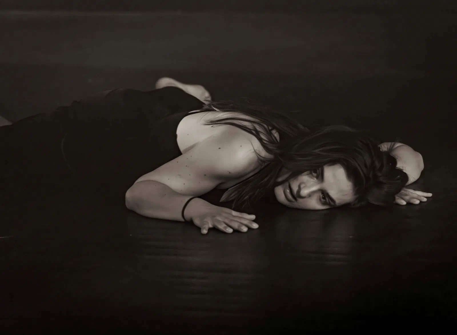 Femme allongée sur un plancher, le regard vers l'objectif